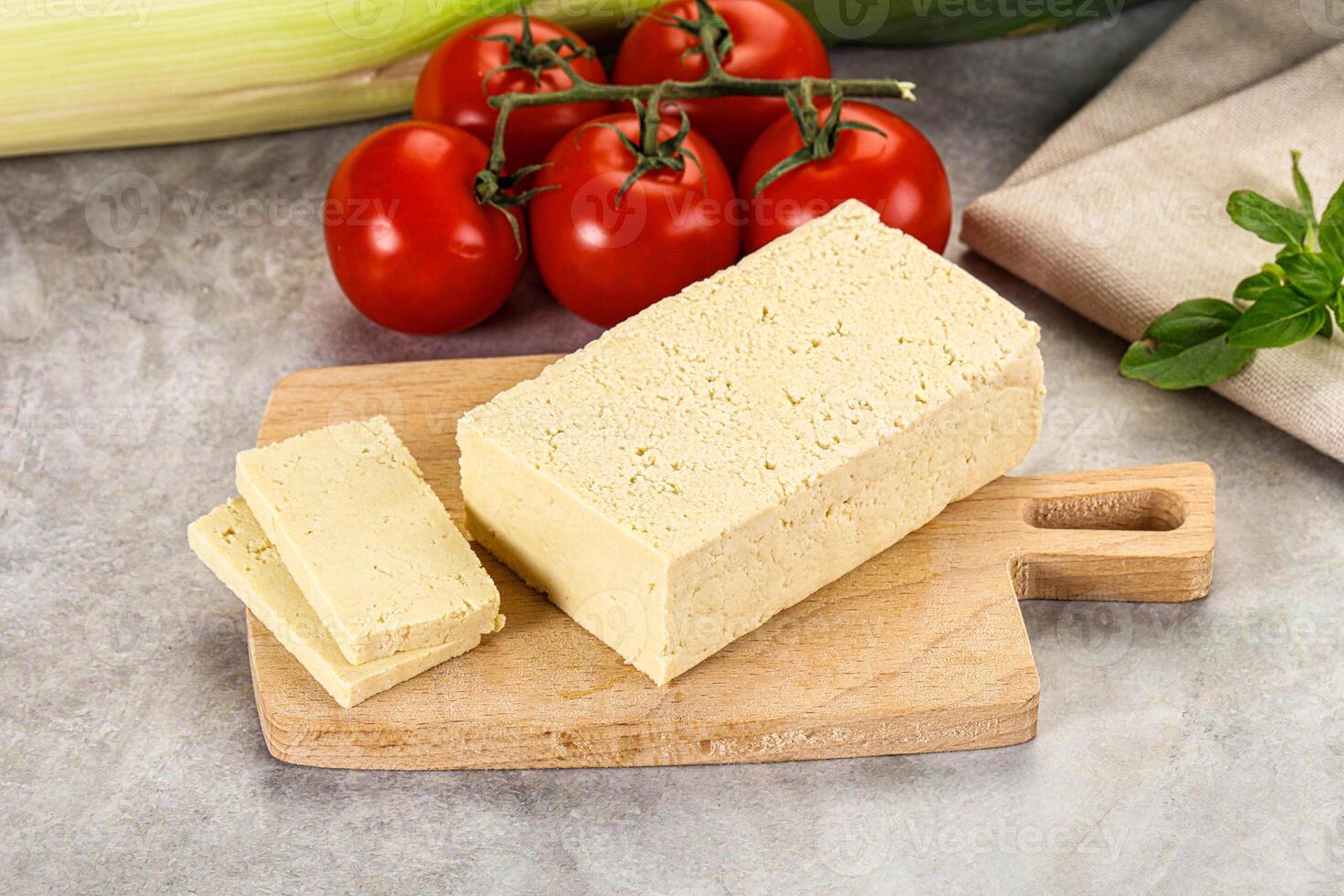 A cutting board with a piece of cheese and tomatoes photo