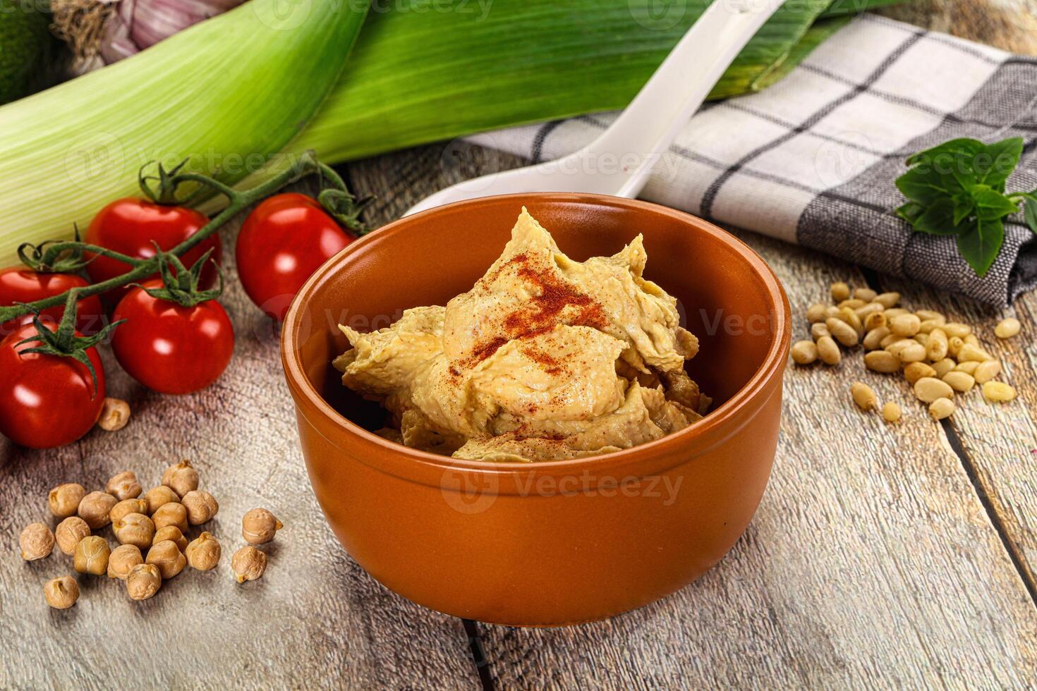 A bowl of hummus with vegetables and tomatoes photo