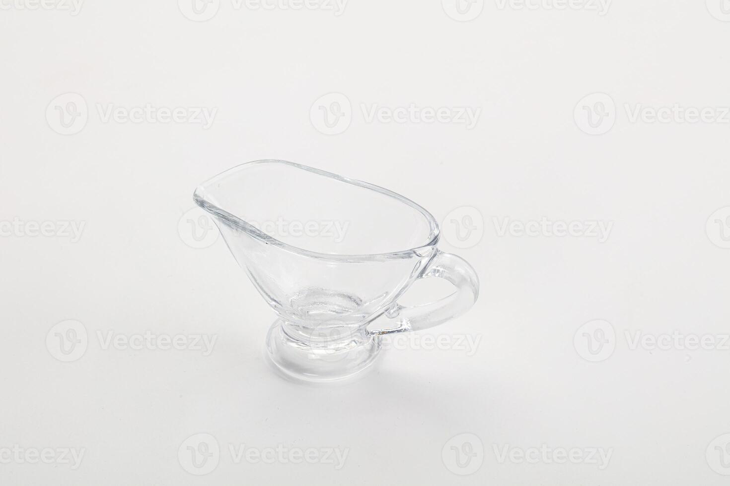 A clear glass pitcher with a handle on a white background photo