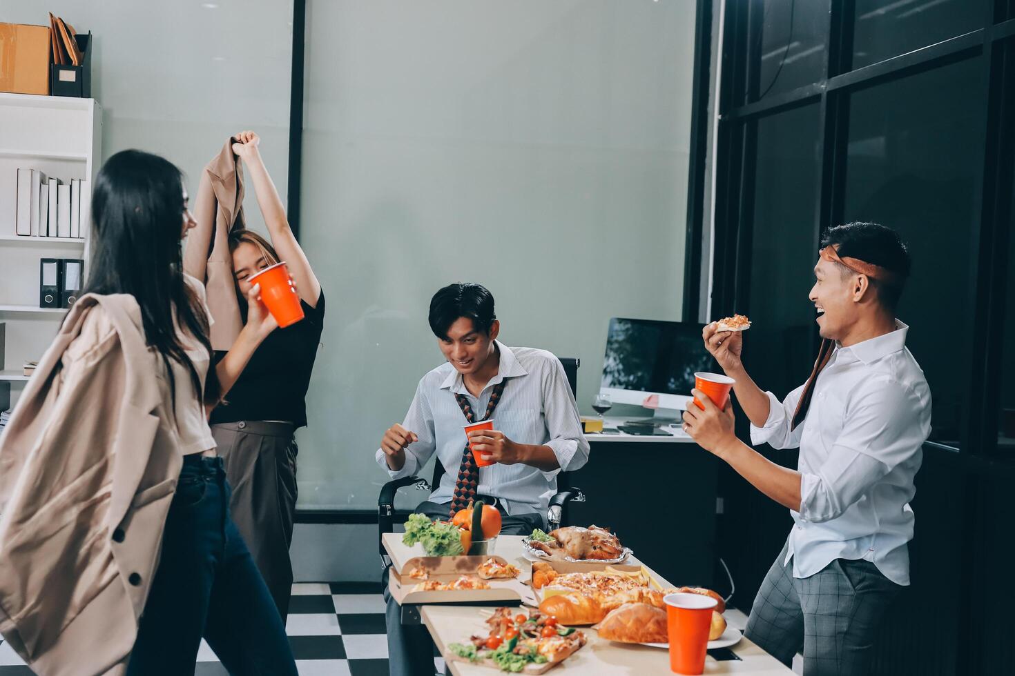 Group of people eating pizza and drinking coffee in an office photo