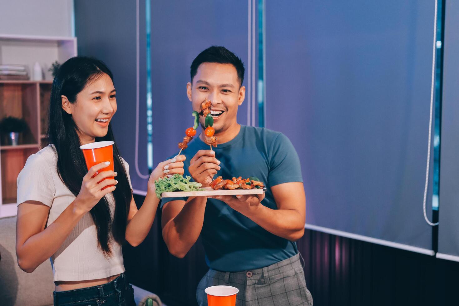 A couple eating food while standing in front of a table photo
