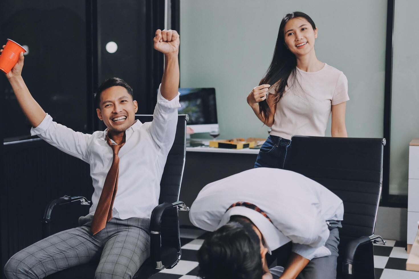 A man and woman are sitting in an office with their arms up photo