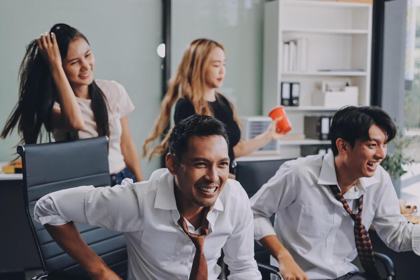 A group of people are laughing and smiling in an office photo