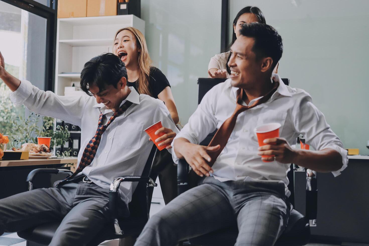 Three people sitting in an office with one man holding a cup photo