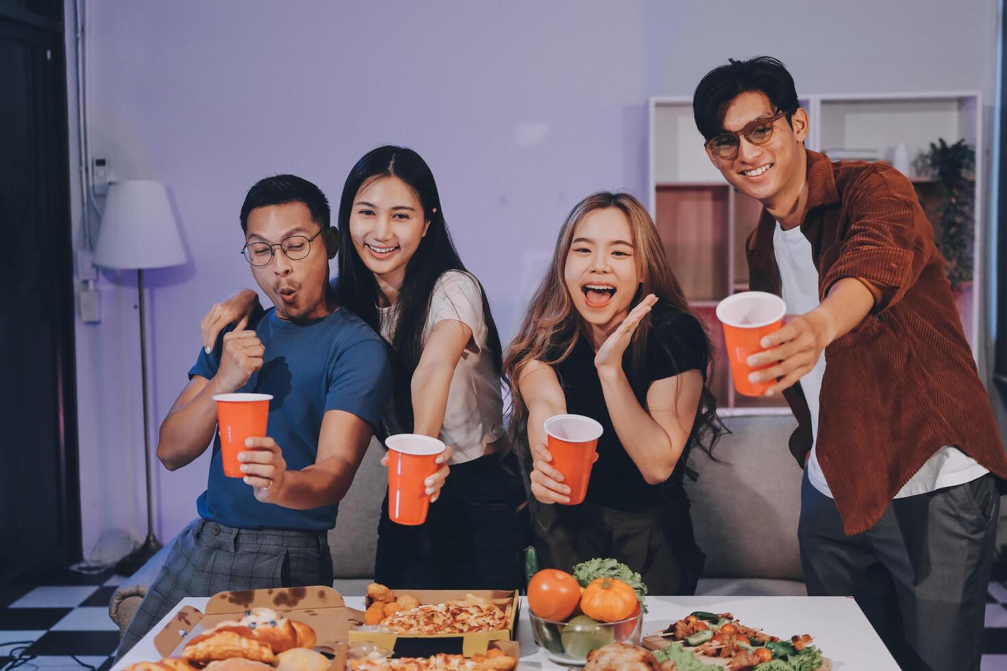 Four people holding up cups of drinks while sitting on a couch photo