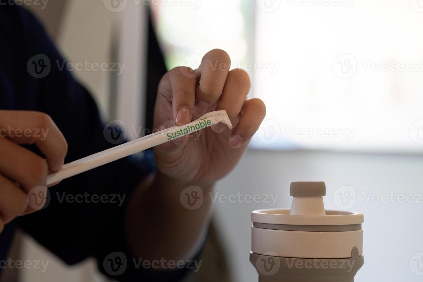 Sustainability and Eco-friendly Practices. A close-up of a person using a sustainable straw with the word Sustainable visible. photo