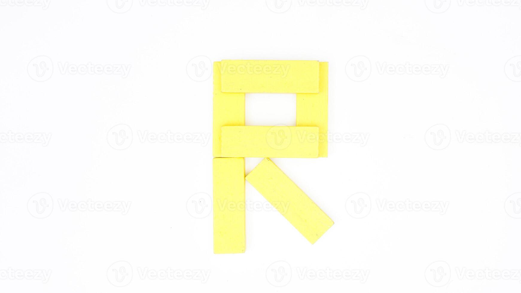 Yellow color wood block formed into letter R isolated on white background photo