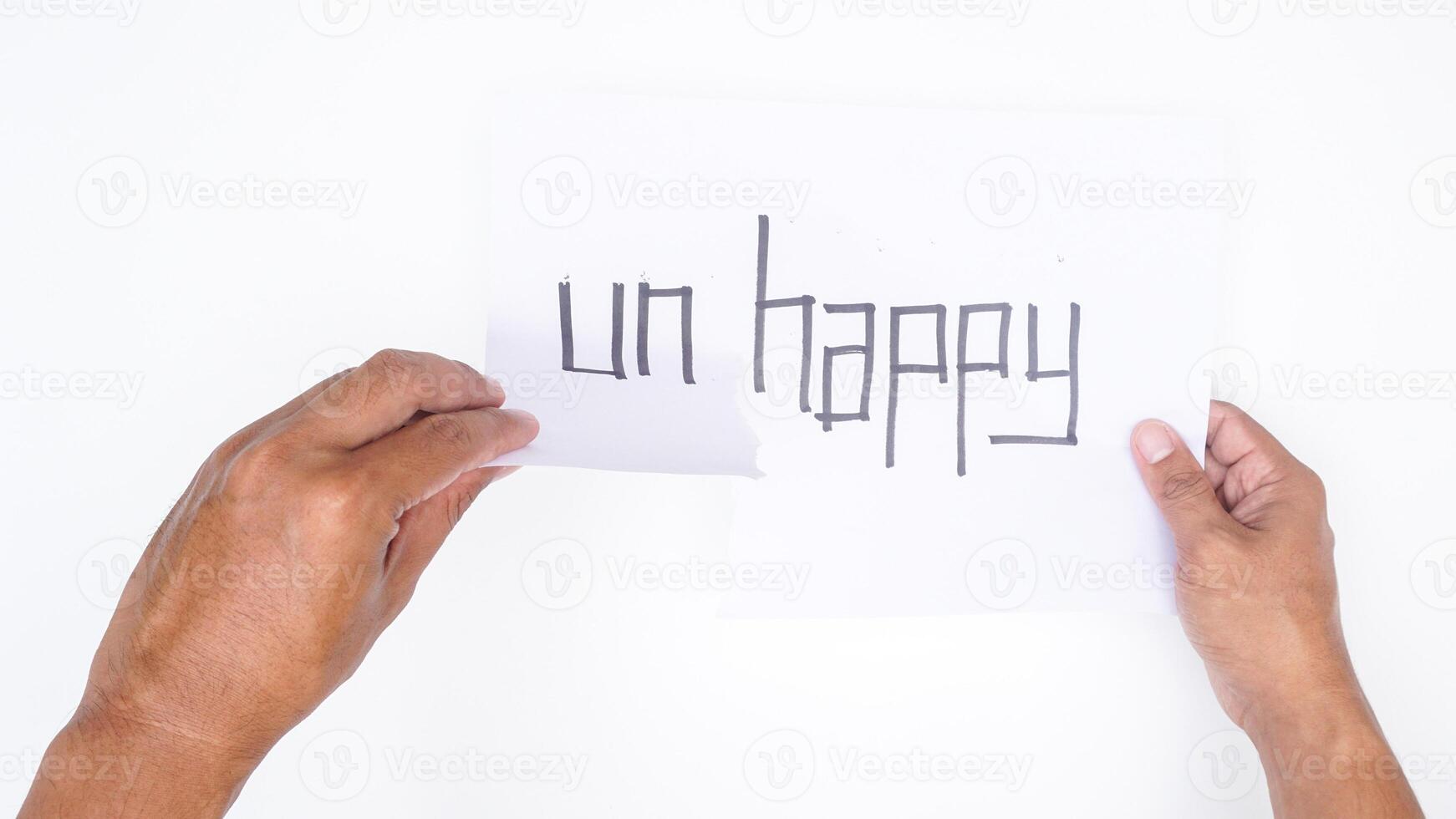 Close up of male hands tearing letters UN from word UNHAPPY isolated on white background photo