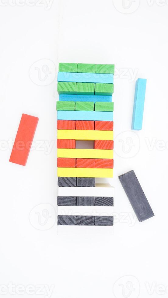Board game tower made of colorful wooden blocks isolated on white background photo
