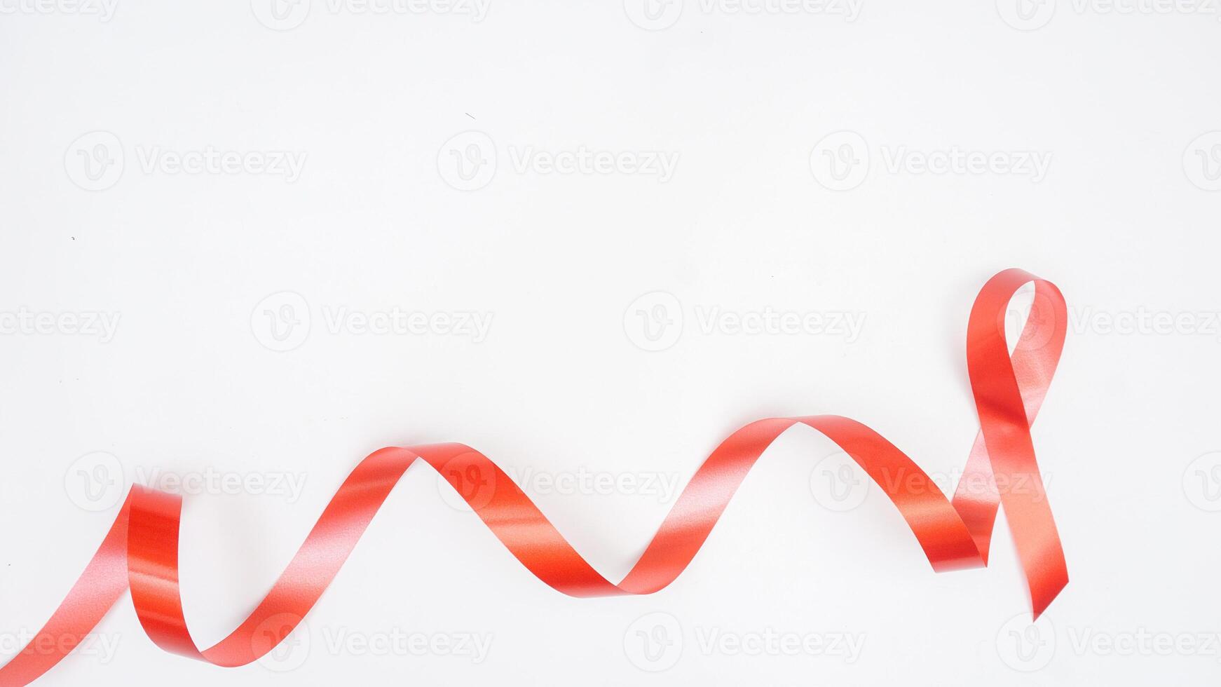 Red ribbon with curly symbol of support for people living with HIV AIDS isolated on white background photo