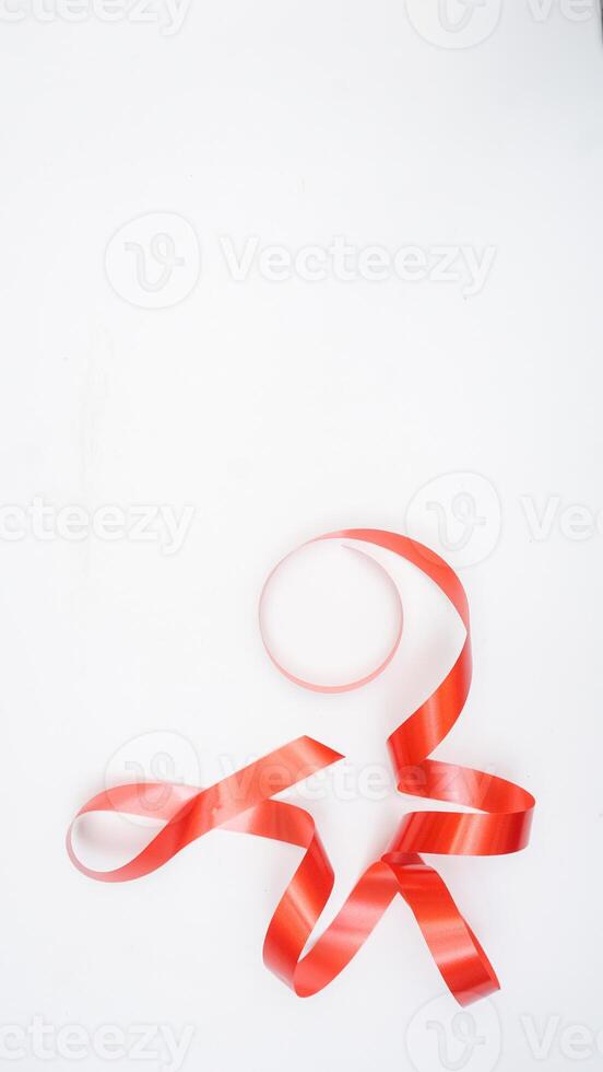 Close up of long curly red ribbon symbol of support for people living with HIV AIDS isolated on white background photo