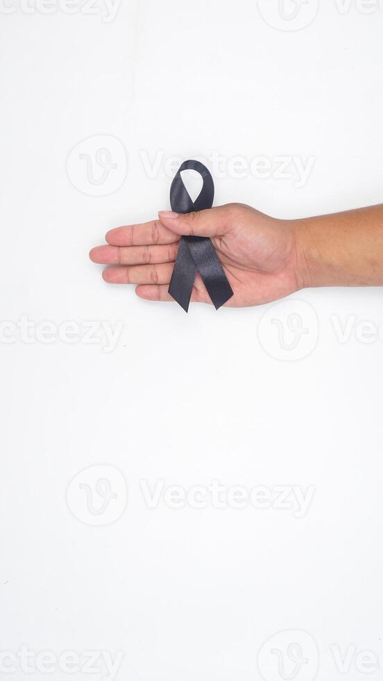 Close up of male hands holding black ribbon as symbol of mourning and melanoma cancer awareness isolated on white background photo