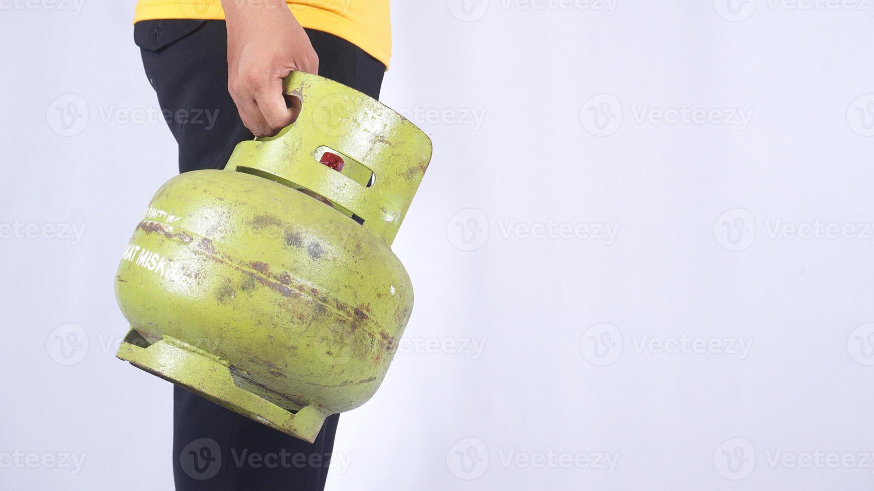 Side view of Asian man holding Indonesia 3kg LPG gas cylinder isolated on white background photo