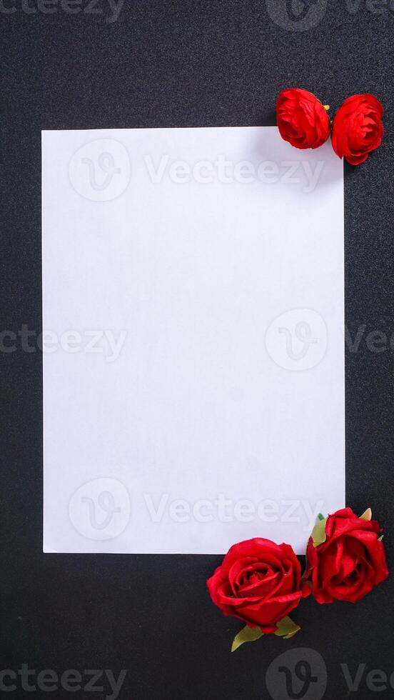 An artificial red rose with blank paper for copy space isolated on black background photo