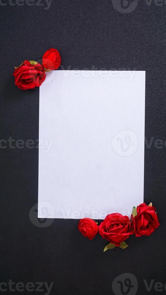 A beautiful artificial red rose with blank paper for copy space isolated on black background photo