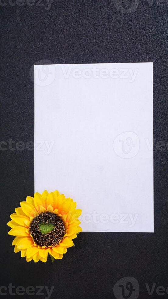 An artificial sunflower with blank paper for copy space isolated on black background photo
