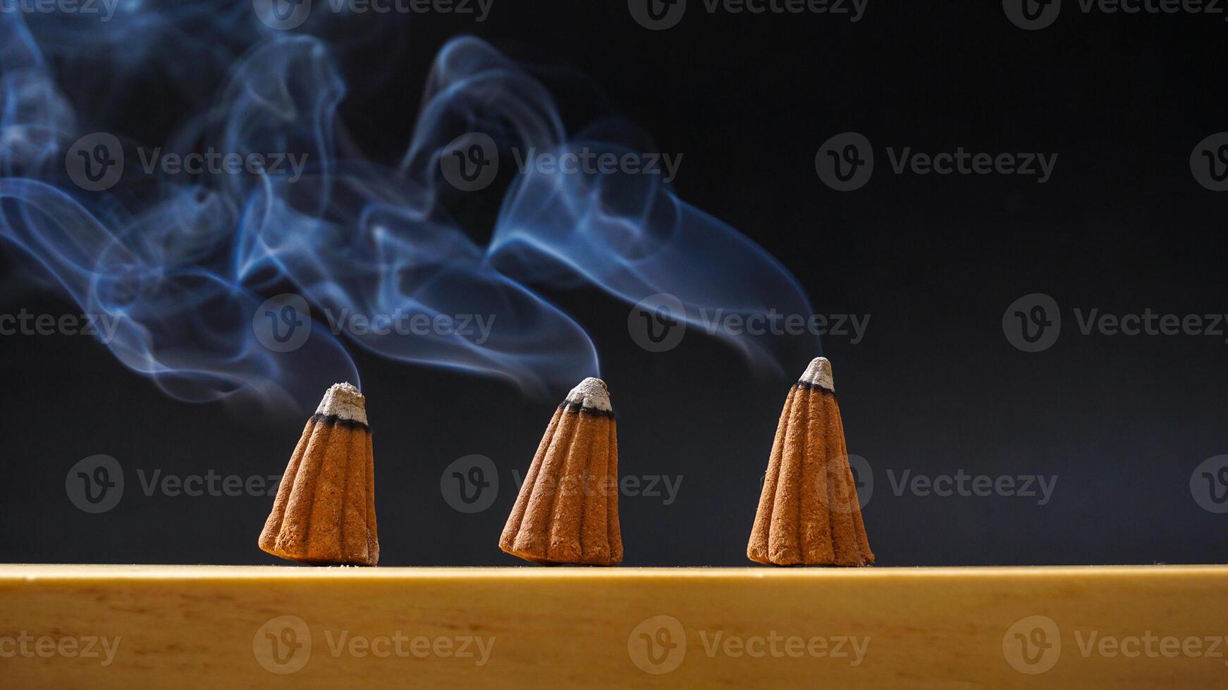Burned incense cones for aromatherapy with smoke isolated on black background photo