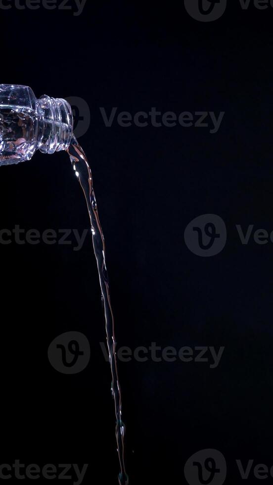 Poured water from bottle isolated on black background photo