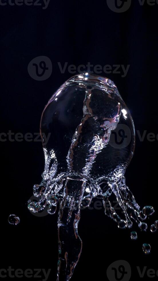Splash of water forming abstract shape isolated on black background photo