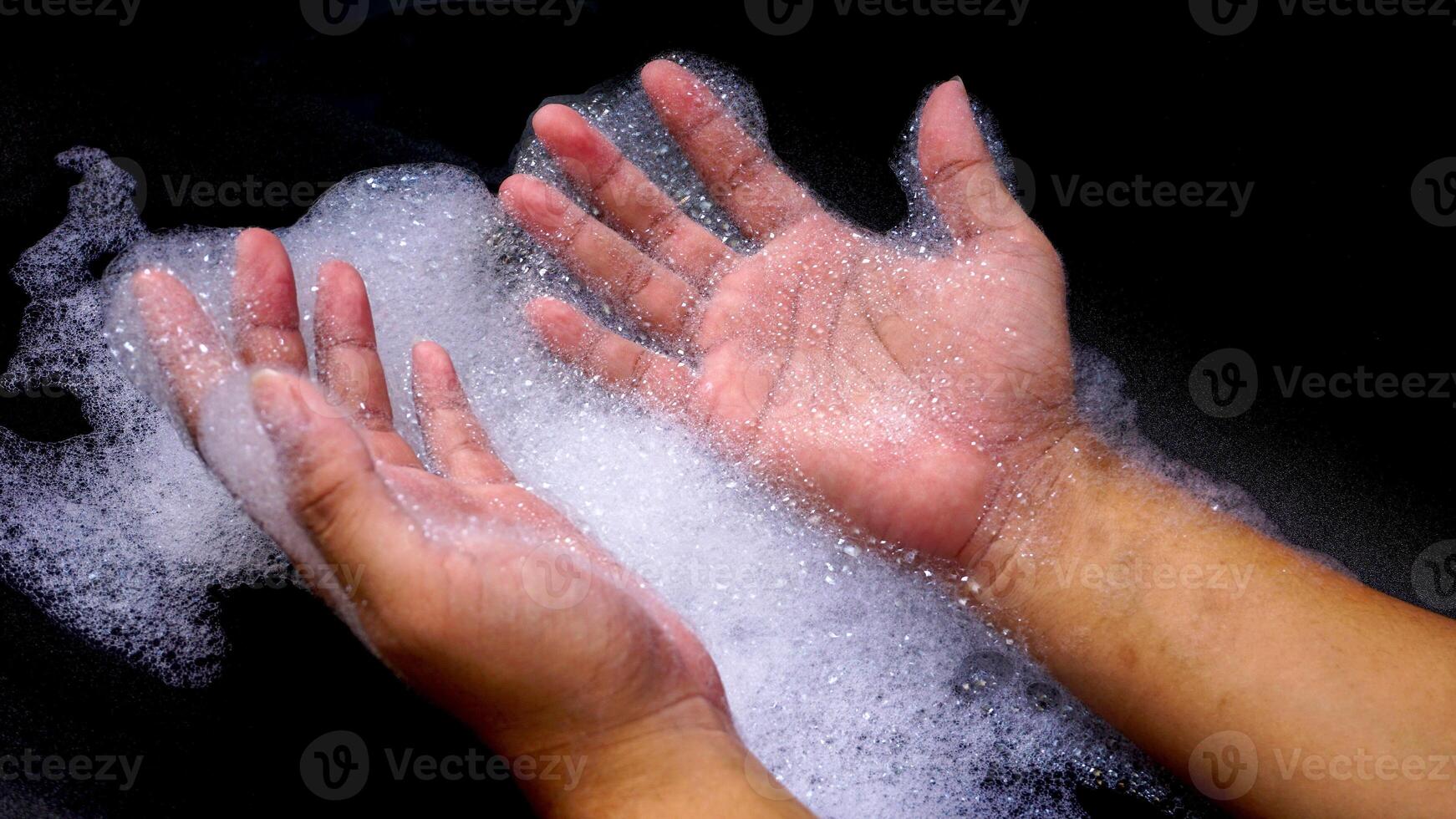 Hands with bubbles foam isolated on black background photo