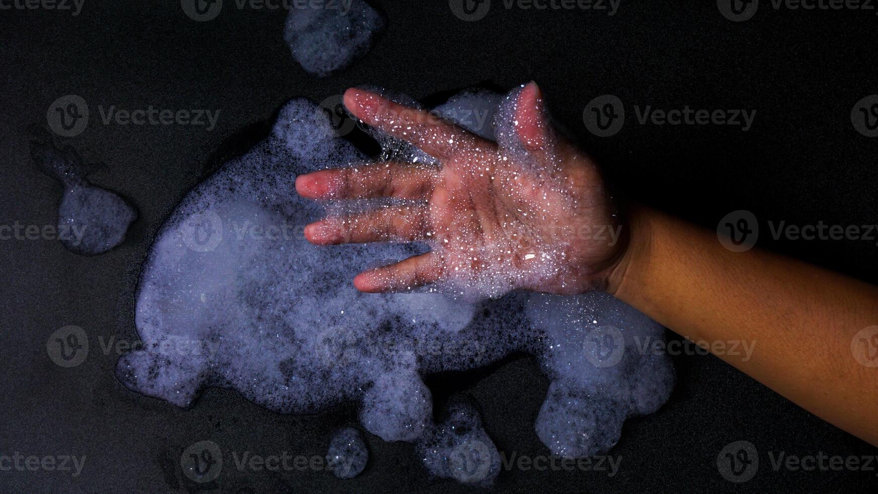Man hand with bubbles foam isolated on black background photo