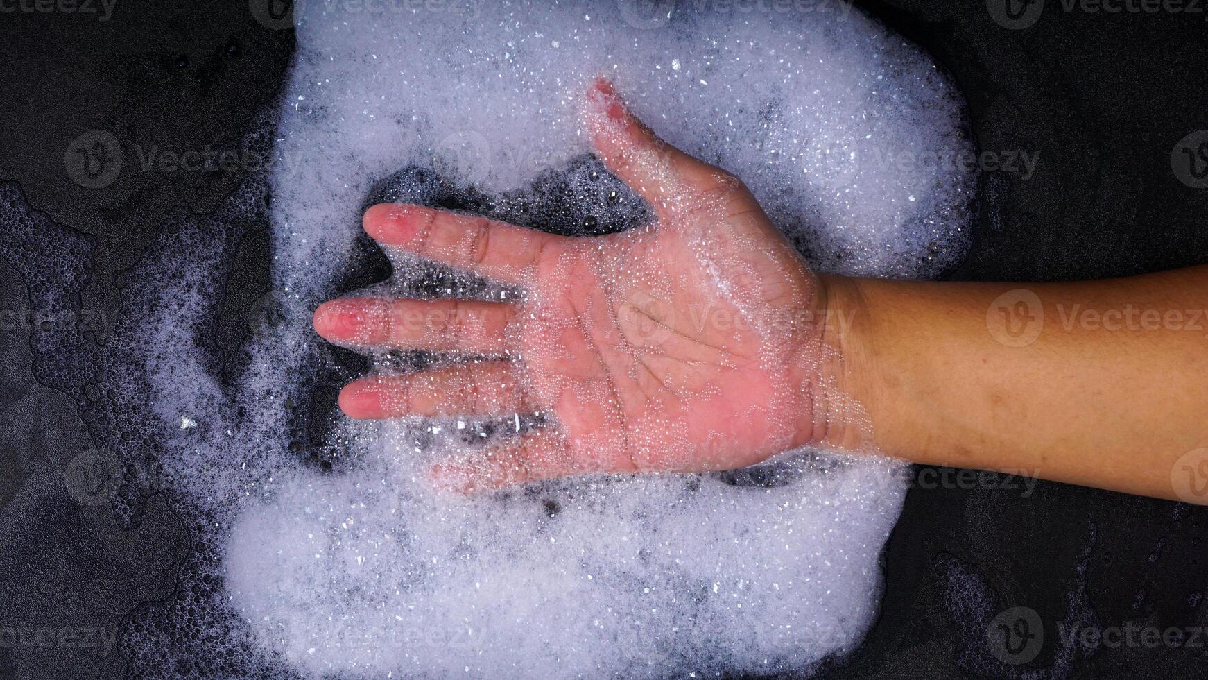 Hand with many bubble foam isolated on black background photo