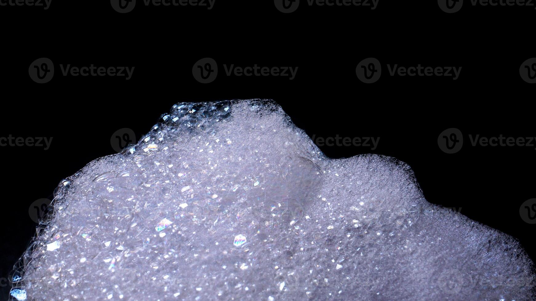 Close up of white foam with bubbles isolated on black background photo