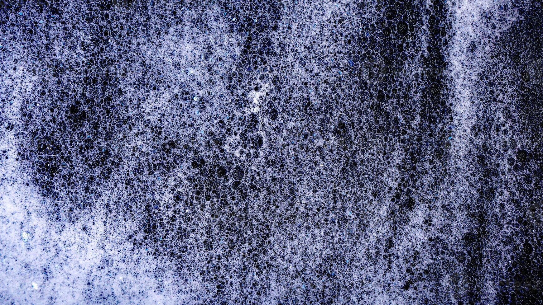 Texture of white bubbles foam isolated on black background photo