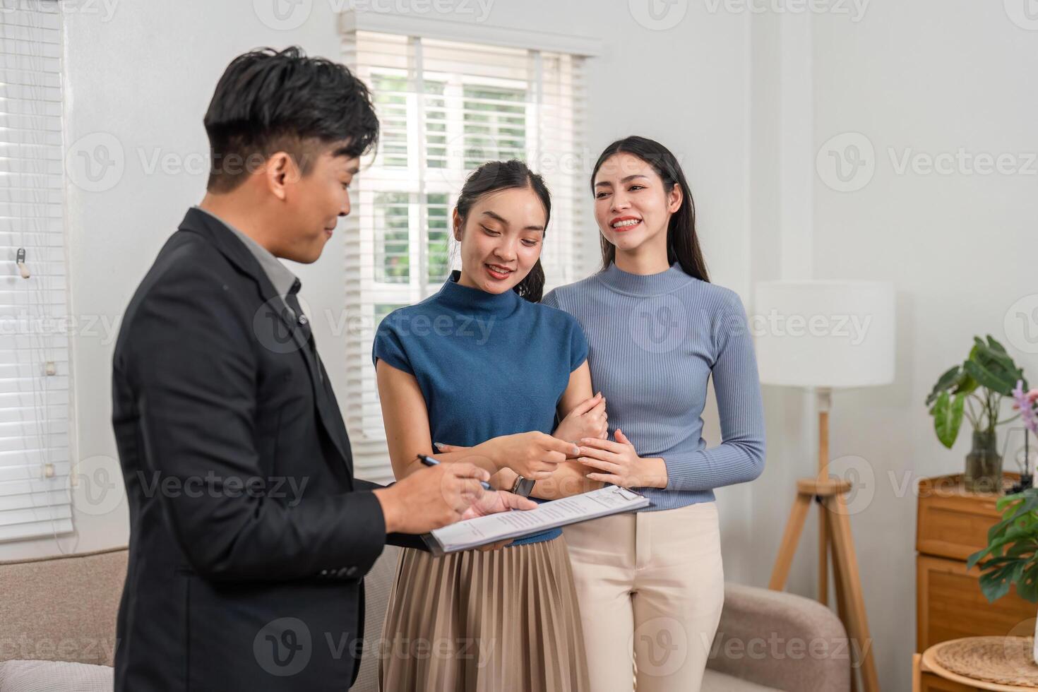 Real estate agent taking notes while discussing options with potential buyers in a stylish living room. photo