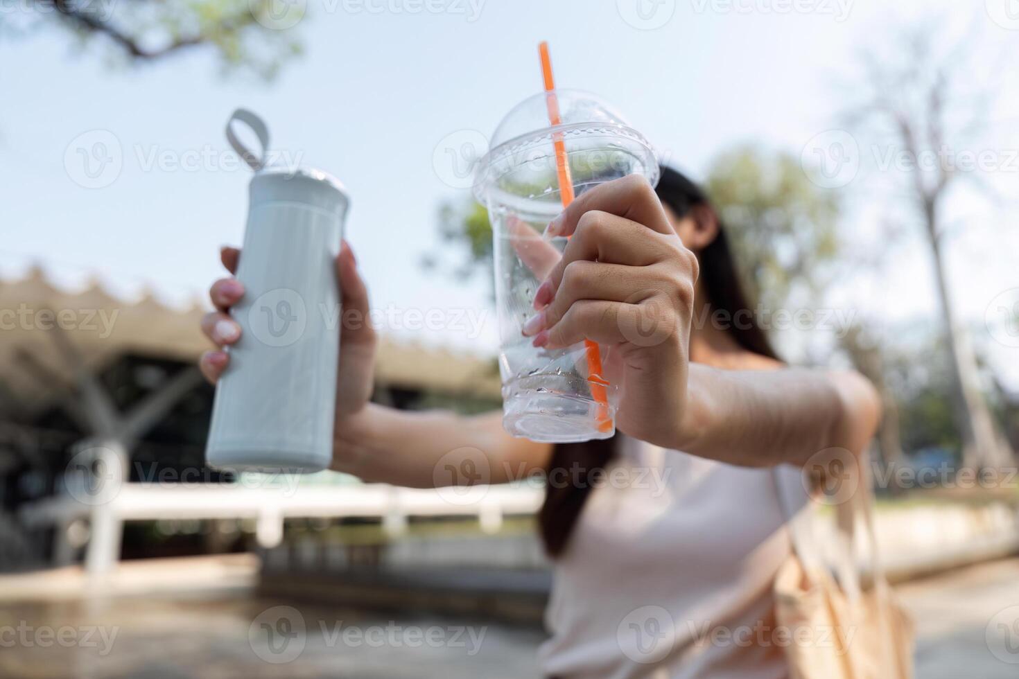 Sustainable hydration. Woman showcasing her eco-friendly drink options in a park. photo