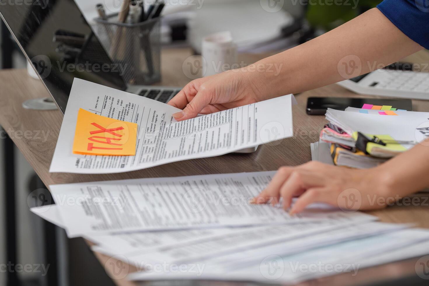 Tax Document Management. Individual organizing tax documents while preparing for filing and calculations. photo