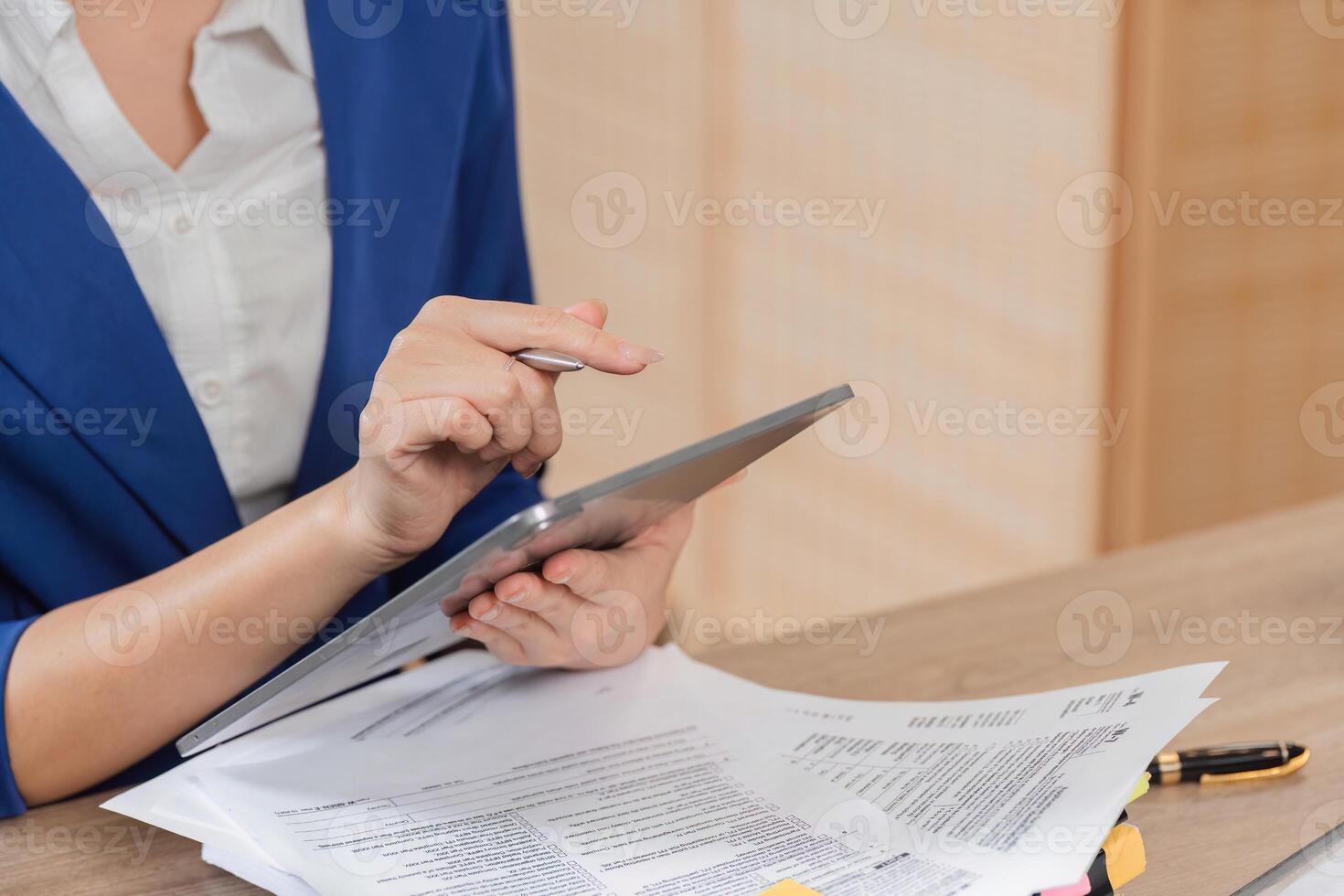 Business and Tax Preparation. Individual reviewing financial documents and using a tablet for tax calculations. photo
