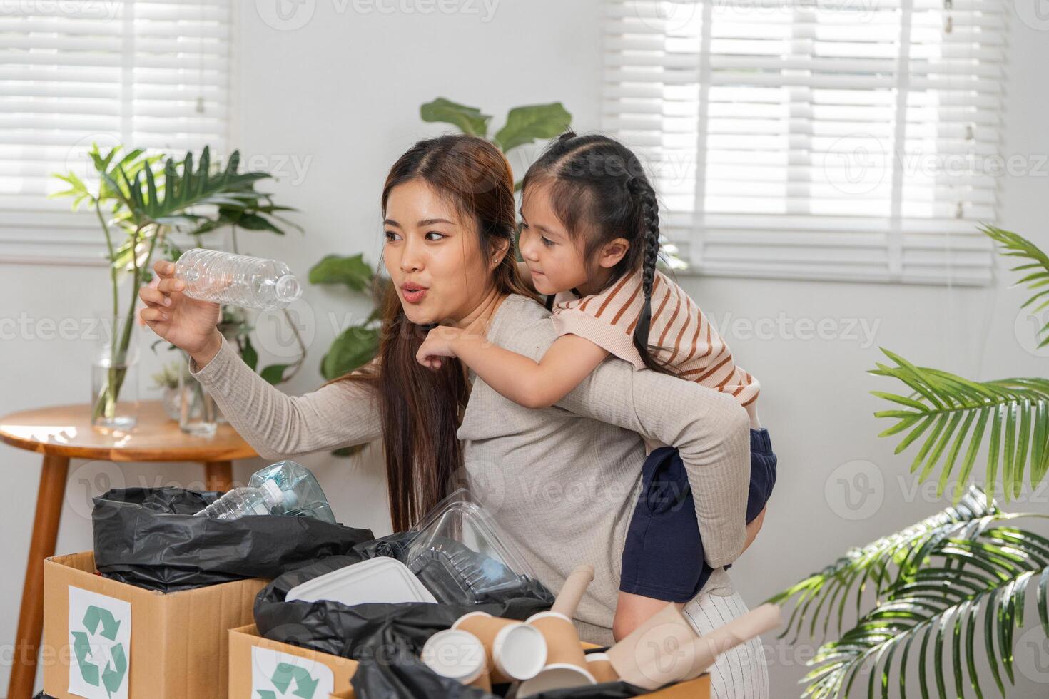 Responsible Parenting and Recycling Education. A mother explains the importance of recycling to her daughter during a sorting session. photo