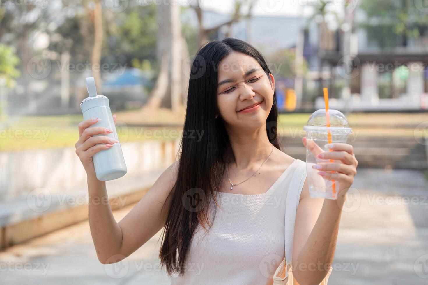 Sustainable lifestyle. Young woman enjoying her reusable cup and bag in a park. photo