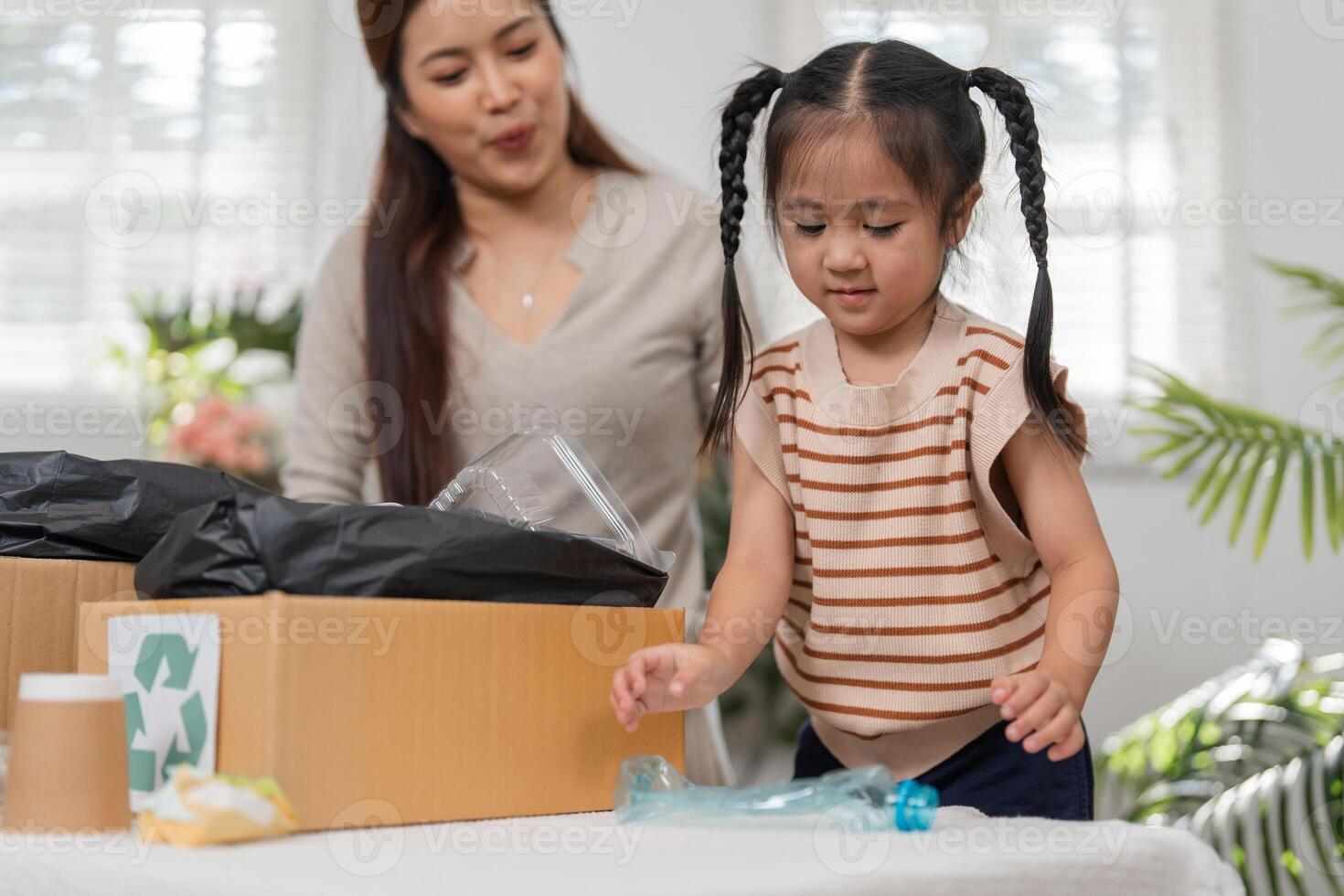 Recycling and Playful Learning. A child excitedly participates in sorting recyclable materials with her mother. photo
