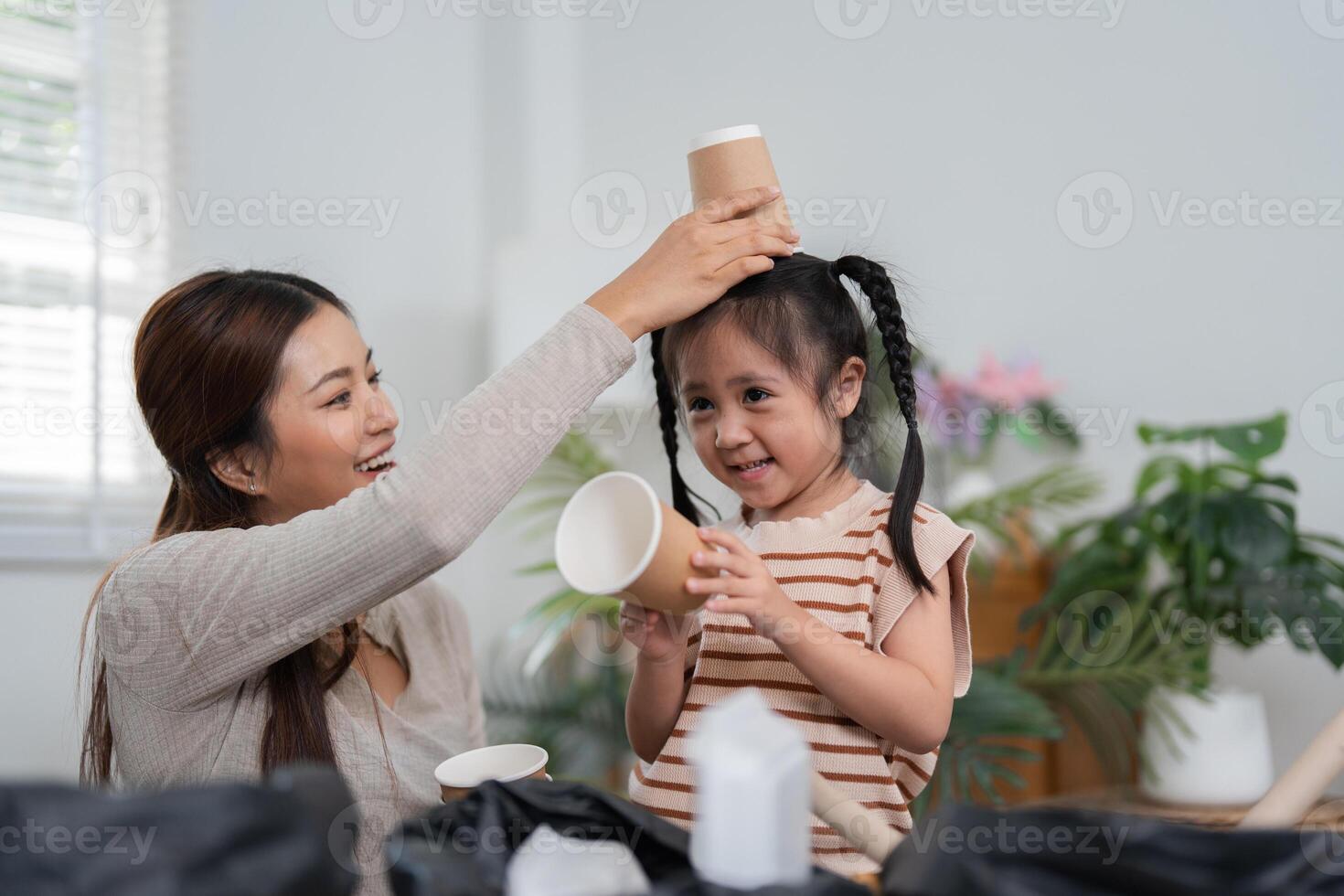 Sustainability and Family Bonding. A mother and daughter engaging in a fun recycling activity with paper cups and containers. photo