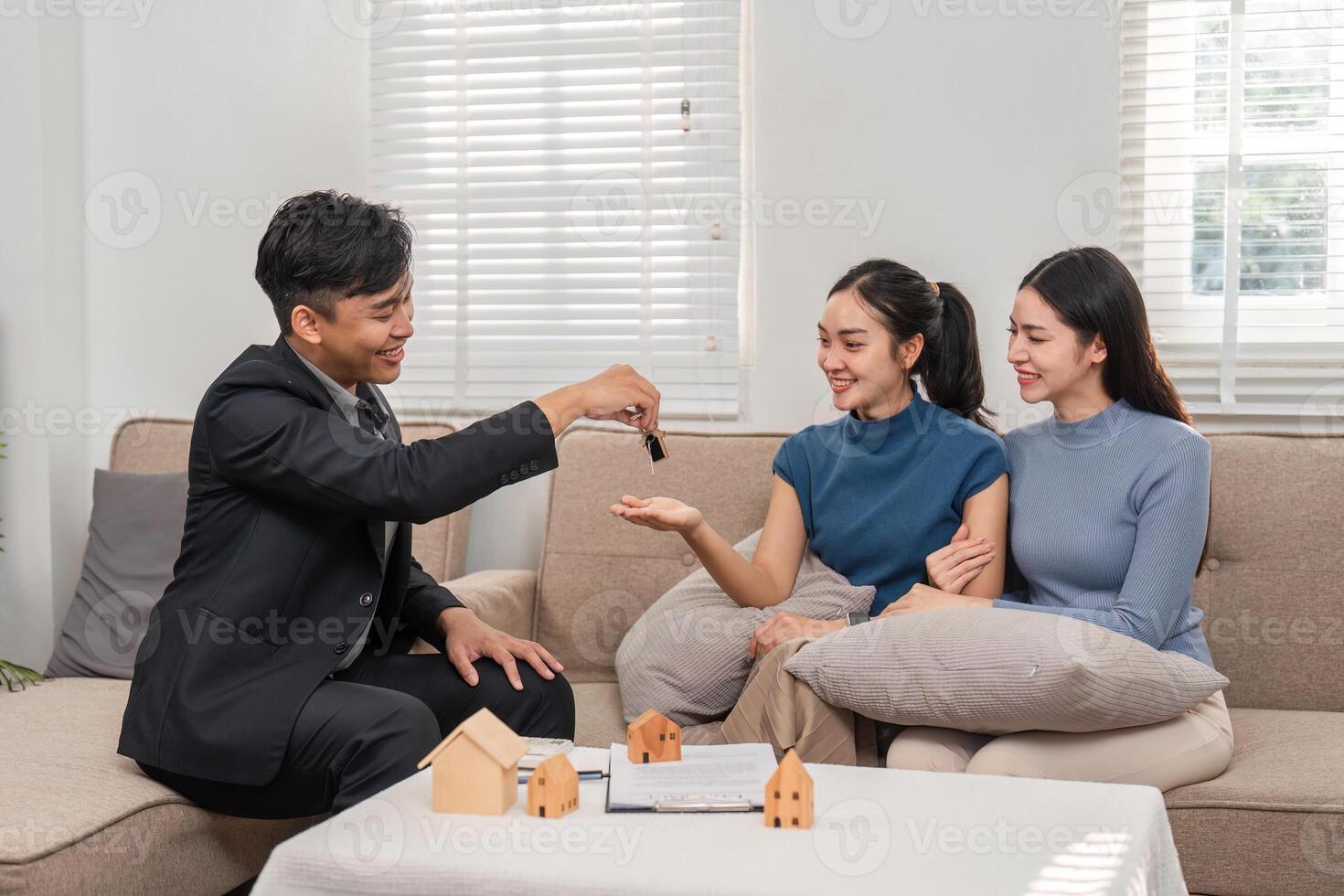 Property Keys Exchange. A real estate agent hands over keys to two excited clients during a property deal. photo