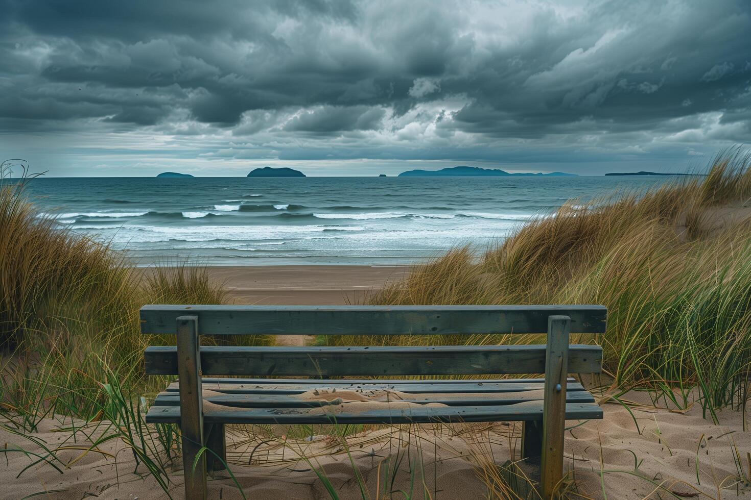 A bench sitting on a beach with a stormy sky photo
