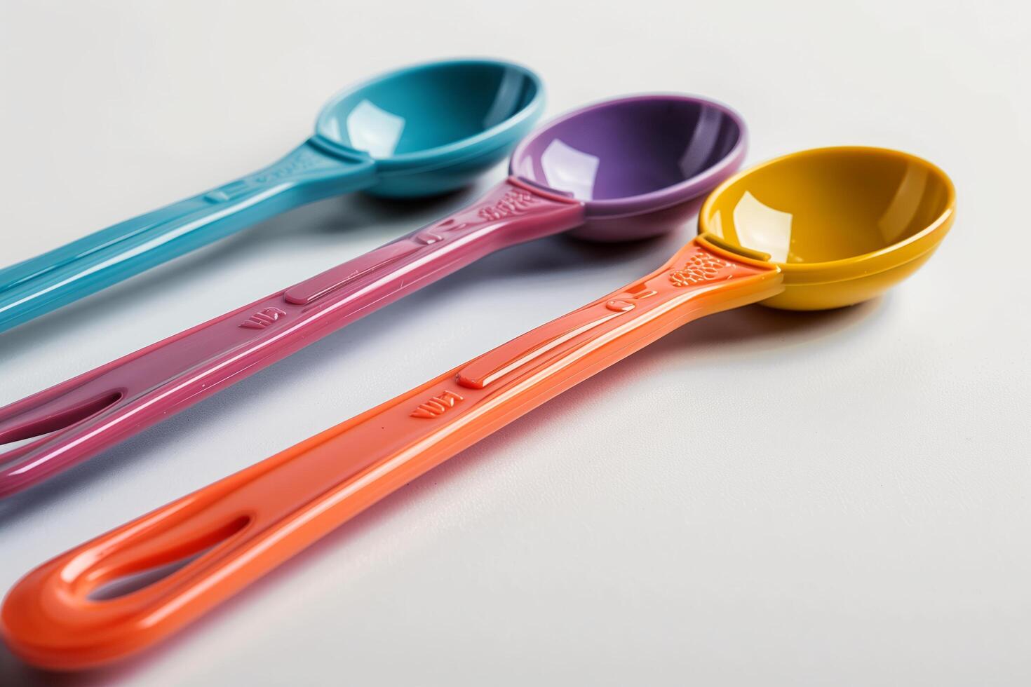 Three colorful spoons are shown on a white surface photo
