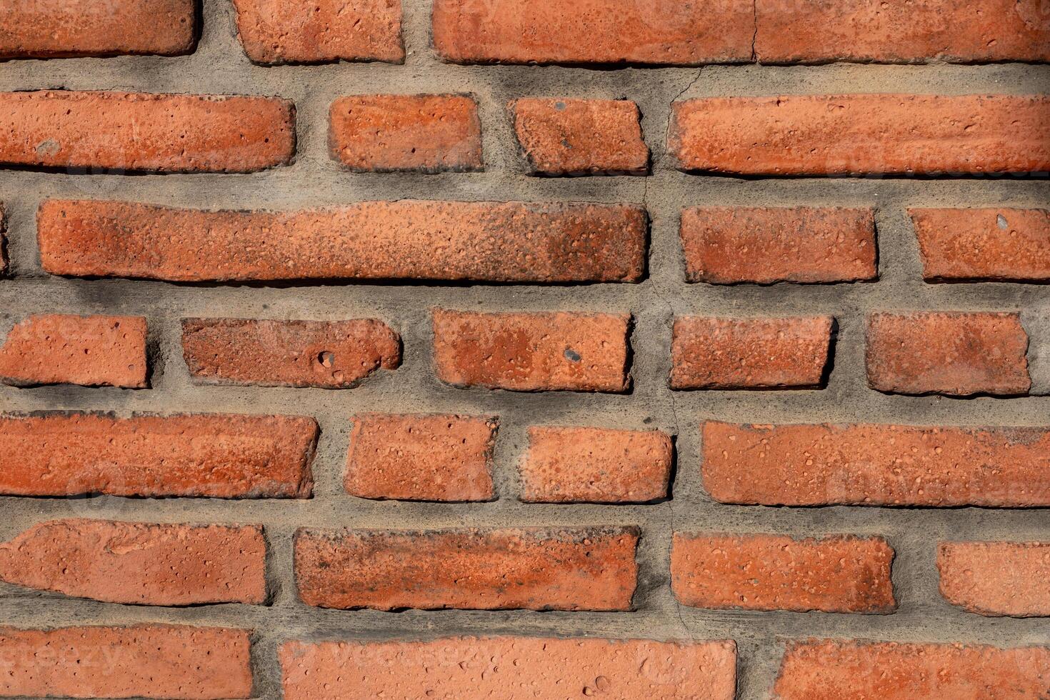 Rustic red brick wall showcasing unique texture and patterns in natural light photo