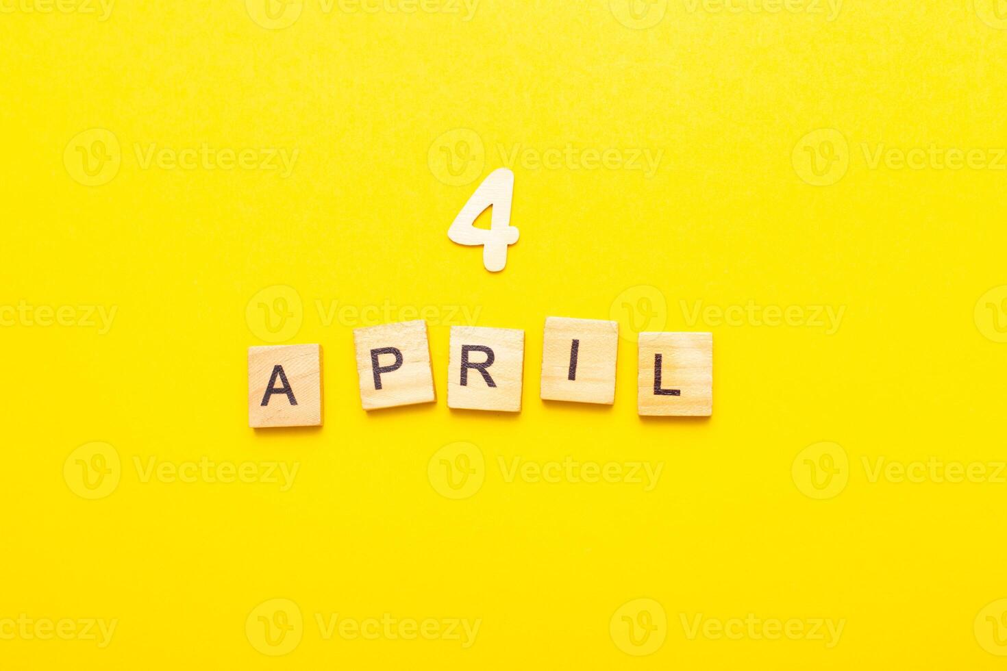 4 April calendar date made by wooden cubes on yellow color background. photo