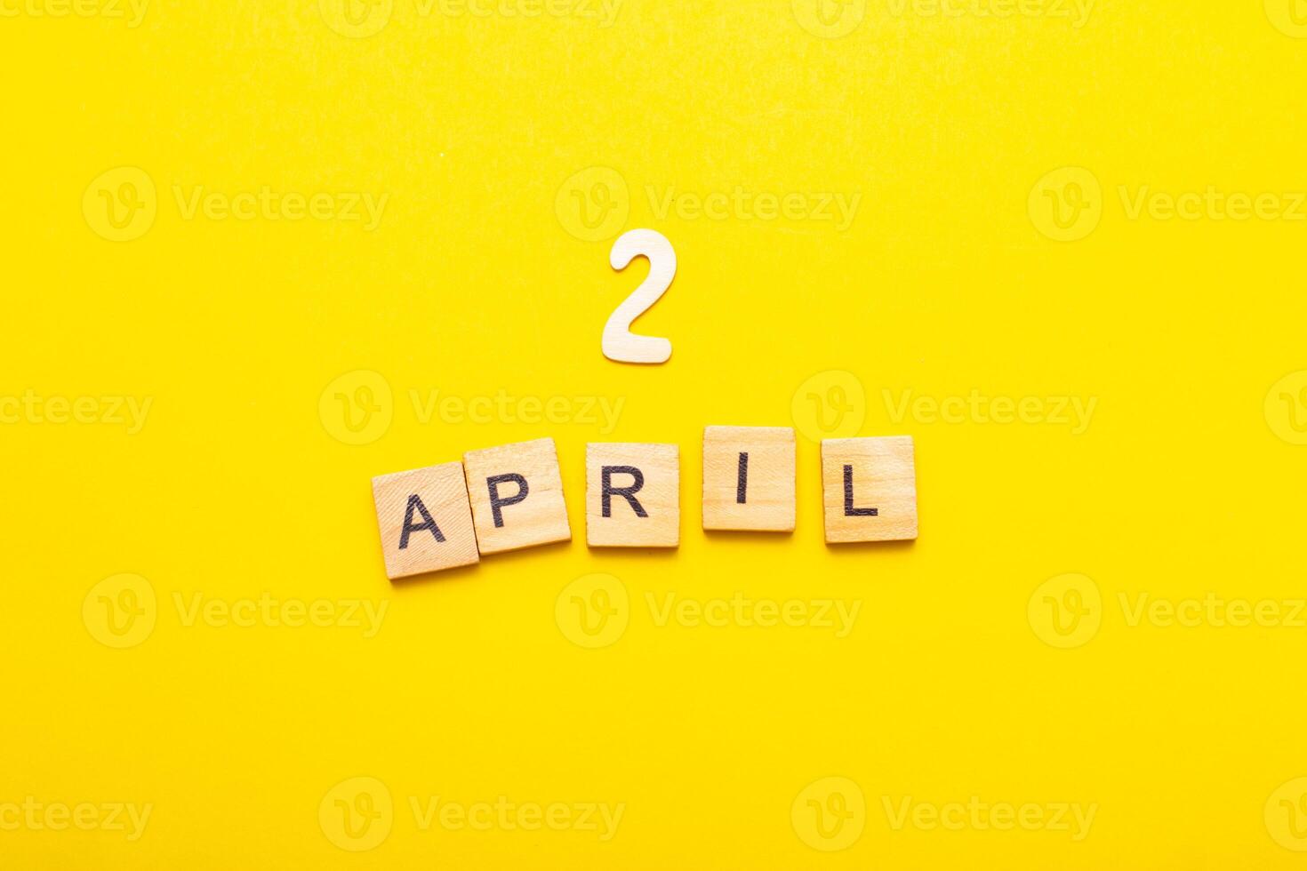 2 April calendar date made by wooden cubes on yellow color background. photo