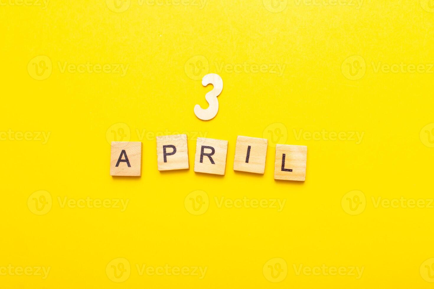 3 April calendar date made by wooden cubes on yellow color background. photo