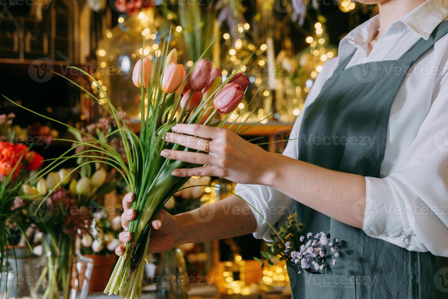 A florist works preparing beautiful floral arrangement. Various flowers and materials lie on table, emphasizing the artistic and inspiring atmosphere associated with floral design and presentation. photo