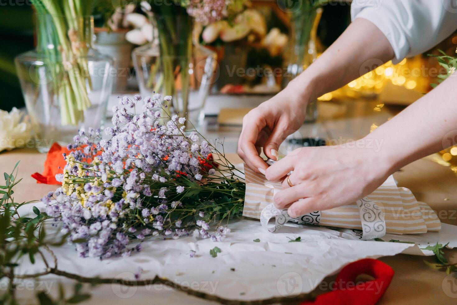 A florist works on preparing beautiful floral arrangement. Various flowers and materials lie table, emphasizing the artistic and inspiring atmosphere associated with floral design and presentation photo