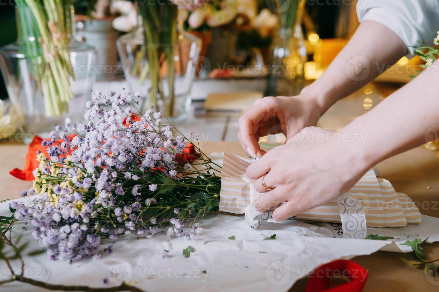 A florist works on preparing beautiful floral arrangement. Various flowers and materials lie on table, emphasizing the artistic and inspiring atmosphere associated with floral design and presentation photo