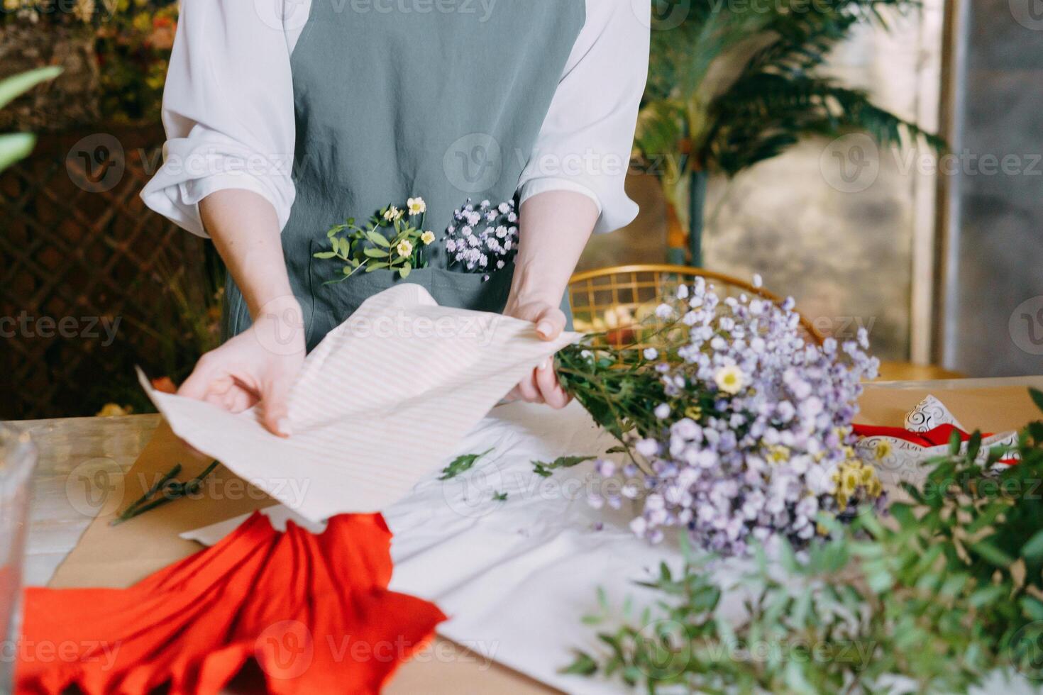 florist works preparing beautiful floral arrangement. Various flowers and materials lie on table, emphasizing the artistic and inspiring atmosphere associated with floral design and presentation. photo