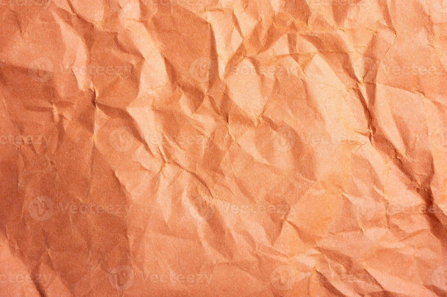 Full frame shot of crumpled orange colour paper sheet texture and background. photo