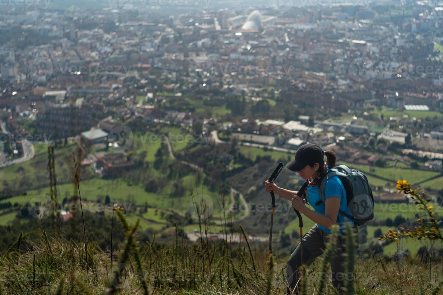 Green landscape in the city of Oviedo in the background, while a woman hikes on the top of Naranco Mountain in Oviedo, Spain. photo