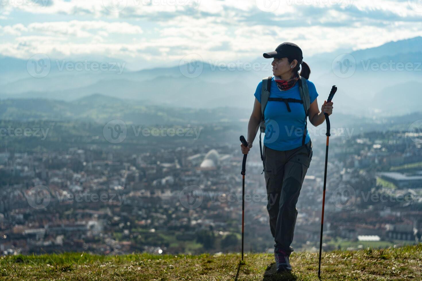 Hiker finishing the climb of Naranco Mountain, while in the background you can see the incredible views of the city of Oviedo, Spain. photo